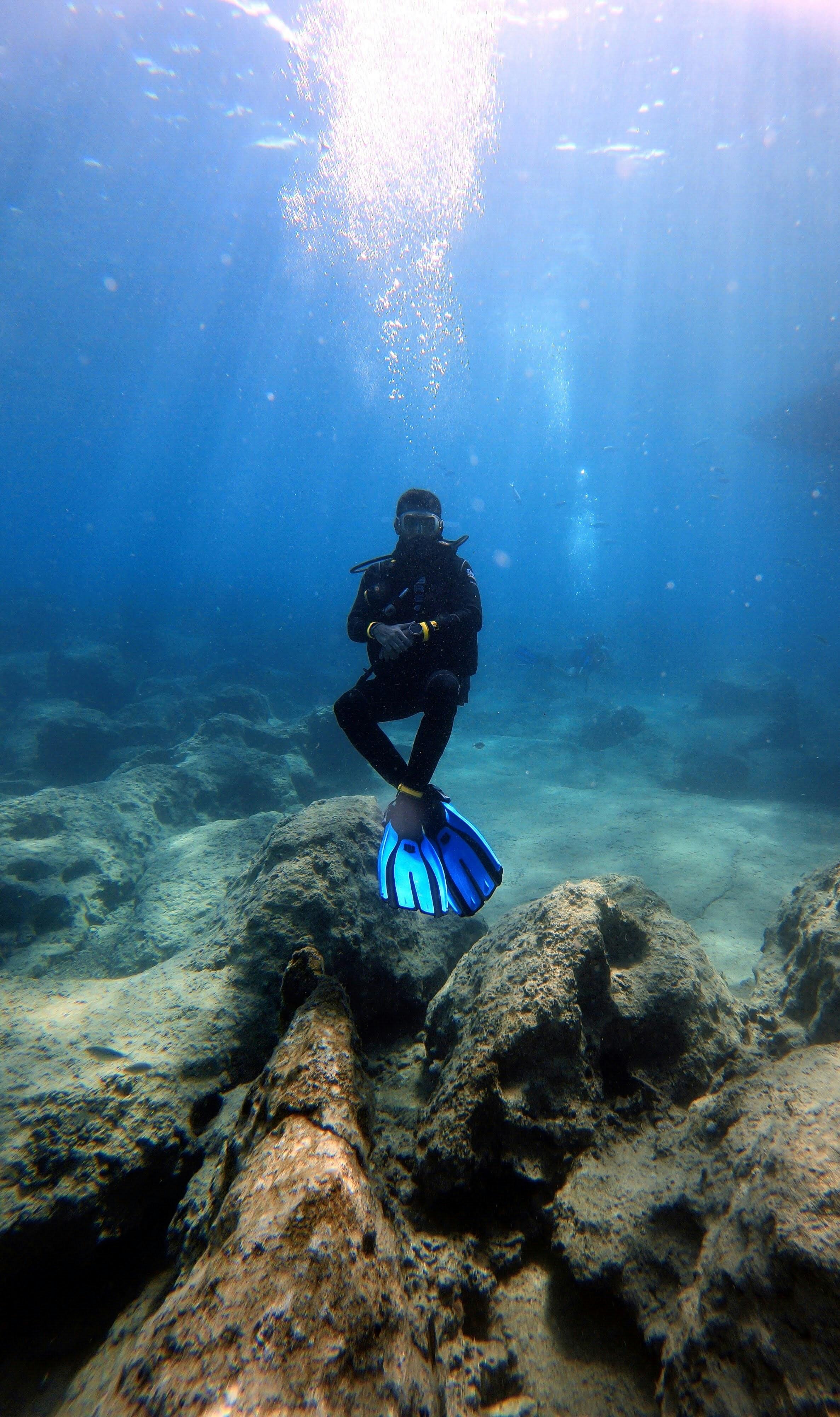 Diver swimming through clear blue water with sunbeams